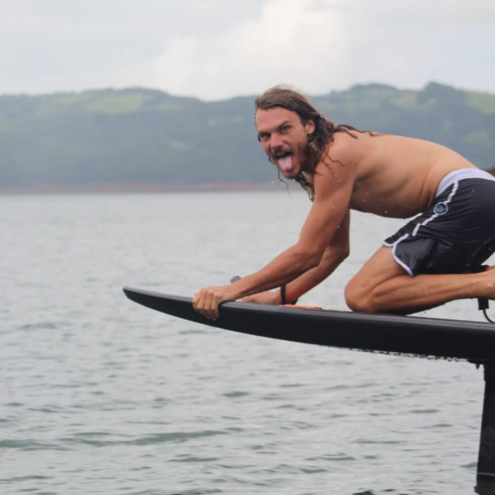 Rider de rodillas sobre la tabla voladora, sonriendo con el pelo al viento