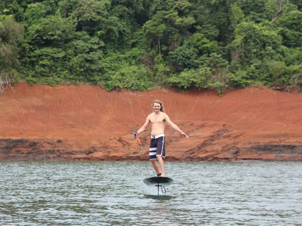 Rider avanzando hacia la cámara con los brazos abiertos sobre el lago